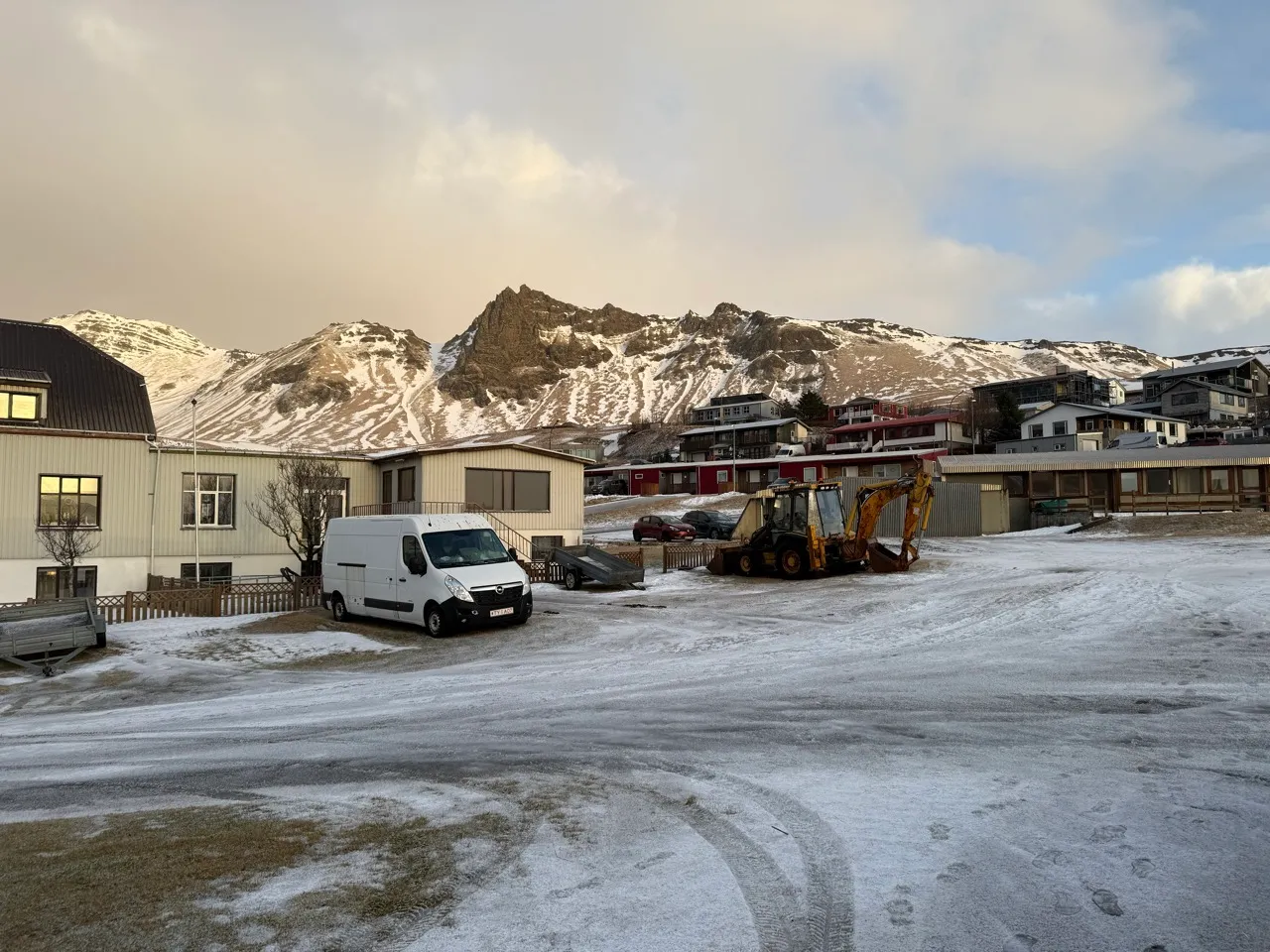 冰島營地的白天景象,數台露營車停在碎石地上,後方是覆雪的山稜