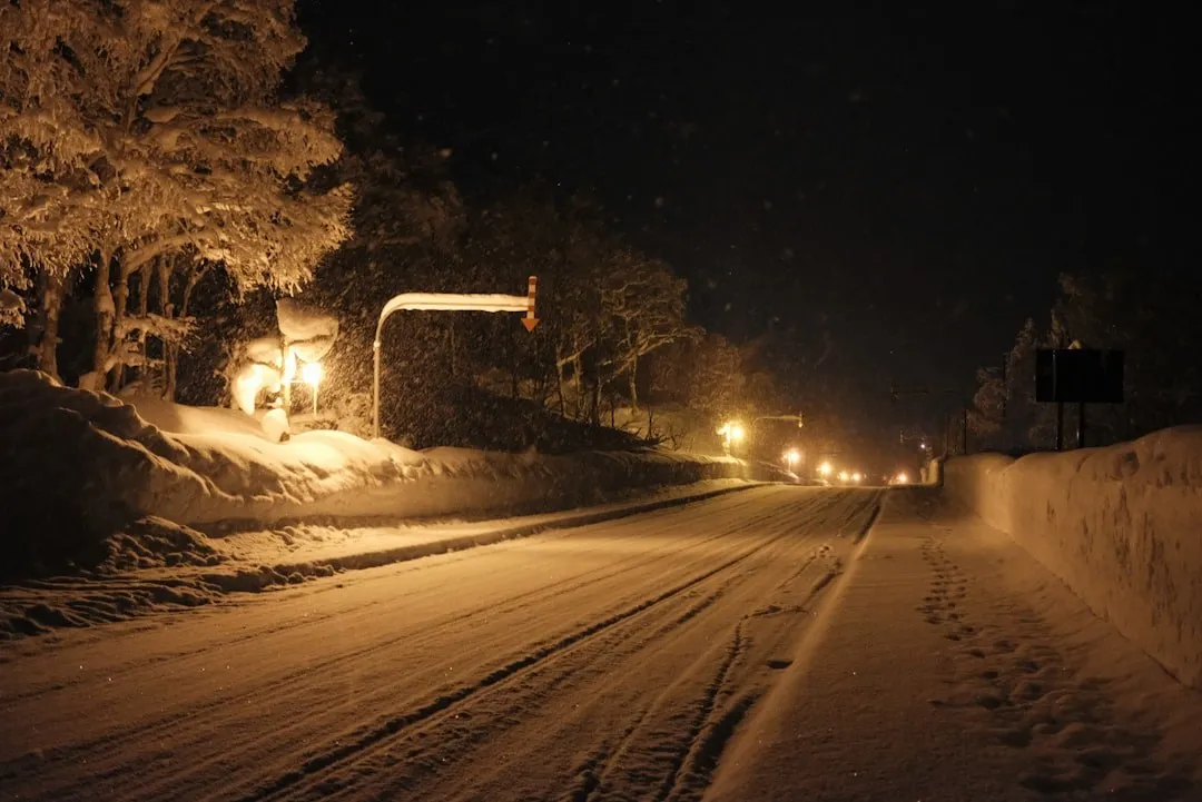 夜色中的小巴停在雪地路邊,車燈照亮前方的積雪道路