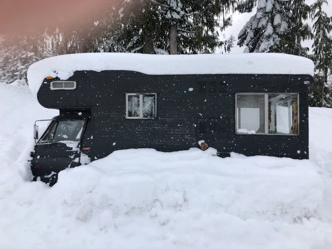 一台露營車幾乎被積雪覆蓋,只露出車窗與側身輪廓