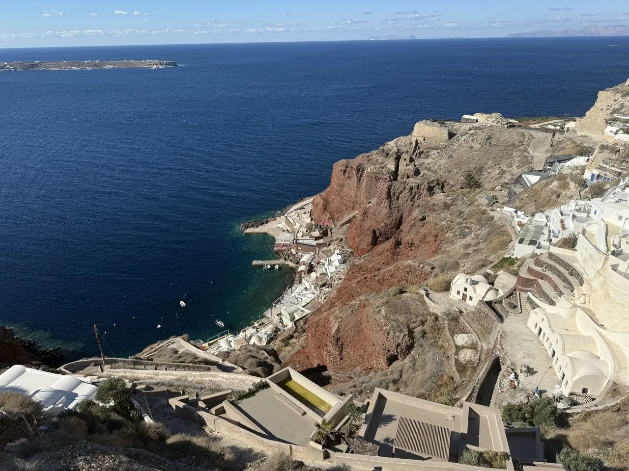Ammoudi 海灣邊的藍色餐桌沿著岩壁排開,海面停著幾艘小漁船