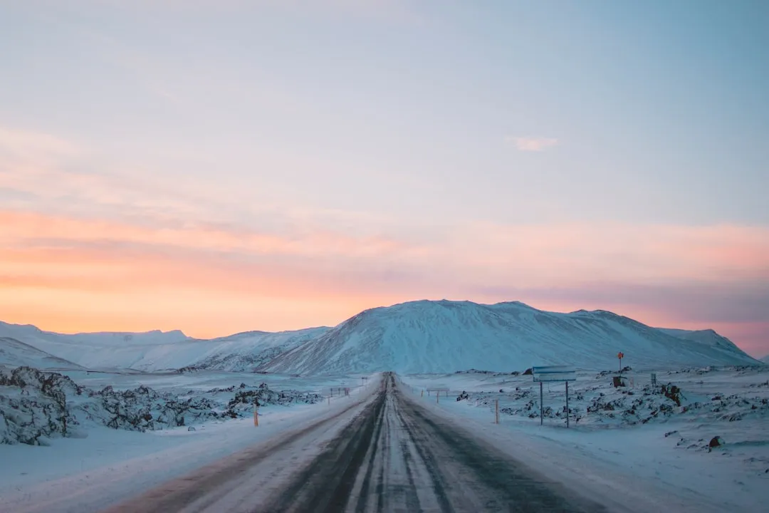 冰島雪地公路筆直延伸向遠方雪山,晨昏的低角度光線