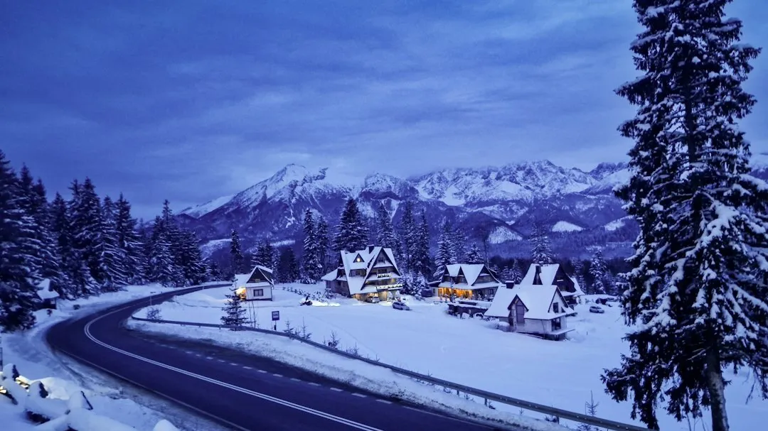 雪地上的公路延伸向遠方山谷,路面有車轍,天空是深藍色