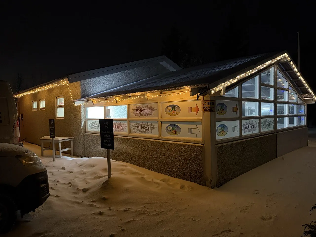 冰島營地的小屋在夜裡亮著暖黃色燈光,周圍是積雪的地面