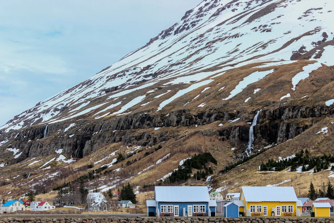 冰島海邊小鎮的彩色房屋沿著海灣排開,後方是覆雪的山坡